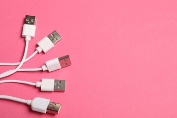 Fototapeta premium USB charge cables on pink background, flat lay. Space for text