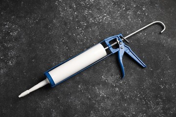 One glue gun on black textured background. Construction tool