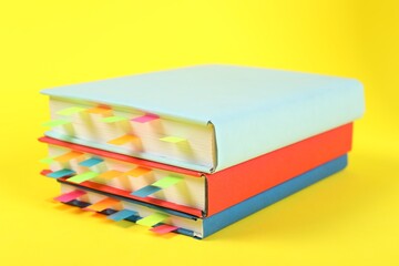 Books with colorful tabs on yellow background, closeup