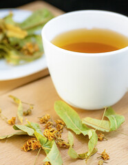 White cup of tea on a wooden board. Linden tea close-up.