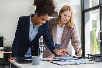 Diverse businessmen write project ideas and use laptops to edit papers for brainstorming sessions with partners in the office.