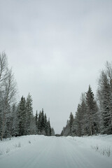 Snow covered road in North Finland on a sunny winter day. Travel Finland landscape background.