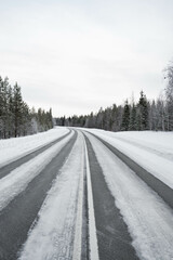 Obraz premium Snow covered road in North Finland on a sunny winter day. Travel Finland landscape background.