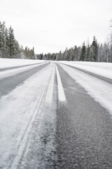 Obraz premium Snow covered road in North Finland on a sunny winter day. Travel Finland landscape background.