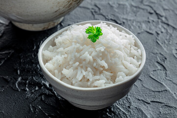 White rice, cooked. A bowl of boiled long grain rice, a simple side dish, with fresh parsley leaves