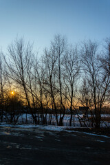 Sunset over the field in the town at winter. Sunny evening,winter landscape. Snow on the groud,beautiful landscape in the town . Orange and blue colors. 