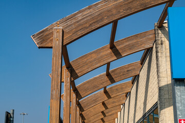 glulam with signs of wear due to time and weather. structure with arched beams and supporting pillars. commercial building designed with structural exposed modules. project, glued laminated timber