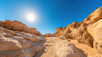 Fototapeta premium stunning desert landscape featuring golden sand and rugged rock formations under bright sun in clear blue sky. scene evokes sense of tranquility and natural beauty