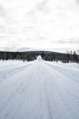 Snow covered road in North Finland on a sunny winter day. Travel Finland landscape background.