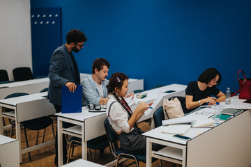 Group of diverse students absorbed in their studies in a bright, modern classroom environment. Engaged in reading and writing, they demonstrate focus and collaboration. Ideal for educational and