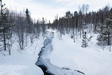 Snow covered river in North Finland on a cloudy day.