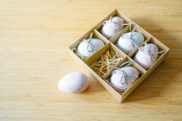 Cardboard box for six eggs, a speckled one is lying outside on a bamboo table, Easter egg concept...