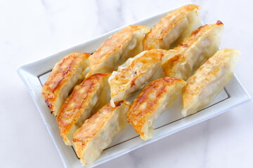 外がパリパリ、中がジューシー、焦げ目がおいしそうな焼きギョウザ
