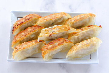 外がパリパリ、中がジューシー、焦げ目がおいしそうな焼きギョウザ
