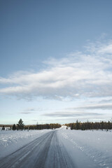 Obraz premium Snow covered road in North Finland on a sunny winter day. Travel Finland landscape background.