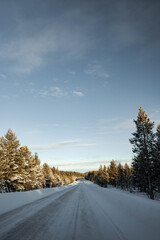 Obraz premium Snow covered road in North Finland on a sunny winter day. Travel Finland landscape background.