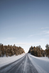 Obraz premium Snow covered road in North Finland on a sunny winter day. Travel Finland landscape background.