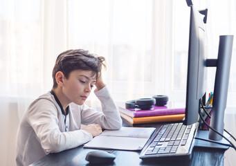 tired little boy 7-9 years old doing homework at home. Topic distance learning, homework, homework, negative impact of distance learning on psychological health. Topic autism, ADHD,. neurodivergence. 