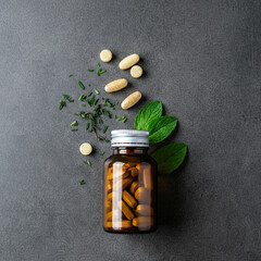 Natural Medicine: Bottle of Pills with Medicinal Herbs and Green Leaves on a soft Background