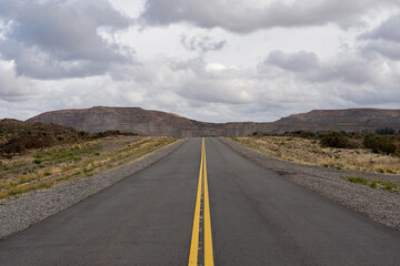 Low angle view of road in remote location in 25 National road surrounded by big red cliffs in Chubut, Argentina