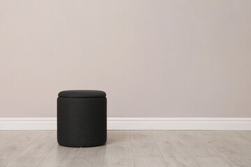 Stylish pouf near beige wall indoors. Space for text