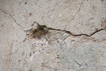 
a cracked concrete wall with a small hole.