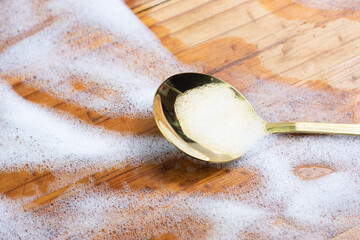 A golden spoon, woven with bubbles, placed on a wooden table