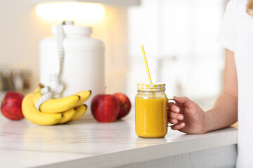 Weight loss. Woman with tasty shake near white marble table in kitchen, closeup