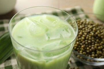 Fresh mung bean juice with ice in glass and seeds on table, closeup