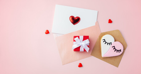 Love card in blue envelope and heart shaped cookie with gift box, mothers day, valentines day on pink background, copy space