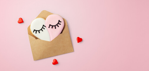 Heart shaped cookie in paper envelope, love for mothers day, valentines day on pink background, top...