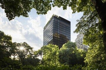 The stock image depicts a sleek, modern office building with glass windows, surrounded by trees in the foreground, bathed in bright sunlight under a clear blue sky