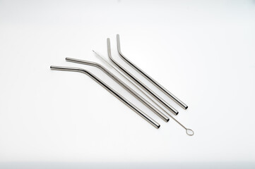 A set of metalic straws and a cleaning brush on white background.