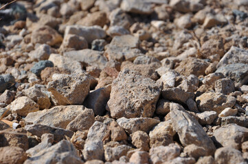 Close-up of a rocky terrain filled with various sized stones in natural shades. The image captures the rugged, textured surface of the rocks, showcasing the diversity and raw beauty of nature.