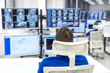 Security officer monitoring multiple surveillance screens in a high-tech control room for safety...