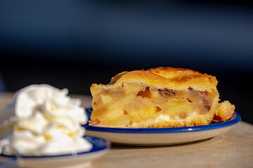 Selective focus of homemade apple pie in the plate served with whipping cream on the side, A pie in which the principal filling ingredient is apples, The earliest printed recipe is from England.