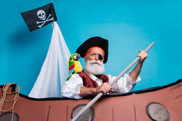 Photo of strong brave man pirate hero traveling sailing wooden boat isolated on blue color...