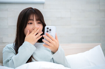 寝起きでスマホを見る日本人女性