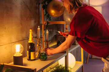 Woman lighting candles for birthday party celebration with champagne and balloons