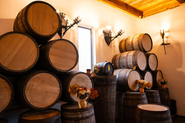 A cozy and atmospheric aging cellar filled with stacked wooden barrels of aged spirits. 