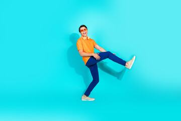 Cheerful young man in vibrant casual outfit posing against a turquoise background, showcasing colorful style and pure joy