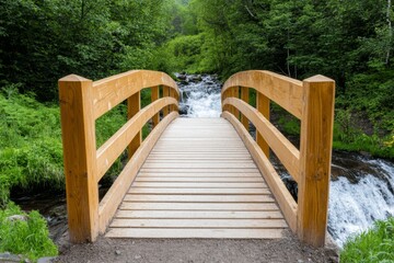 Fototapeta premium A waterfall crashing down with an old wooden bridge crossing above it