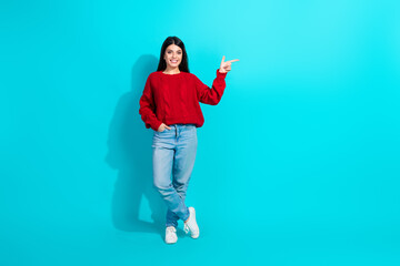 Smiling young woman in a red sweater posing on a turquoise background, gesturing subtly while exuding confidence and charisma