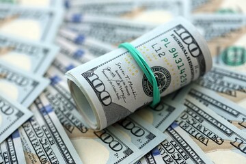 Roll of hundred dollar bills USD banknotes lies on big amount of united states money