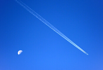 airplane and the moon on a bright blue sky