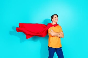 Confident Young Man With Red Cape Posing in Casual Outfit on a Teal Background Exuding Happiness