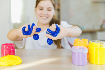 A cheerful little girl immerses herself in creativity, playing with vibrant slime. Each squish and...