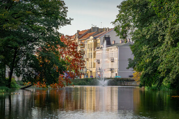 urban landscape view of urban buildings by the Prosne River in Kalisz. urban architecture, old buildings, decorated tenement houses. autumn colors on the trees with reflection in the river.