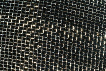 Monochrome texture of a shiny metal colander or grate. Abstract background.
