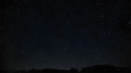 Countless stars shining in the dark night sky over a hill, creating a breathtaking view of nature's beauty